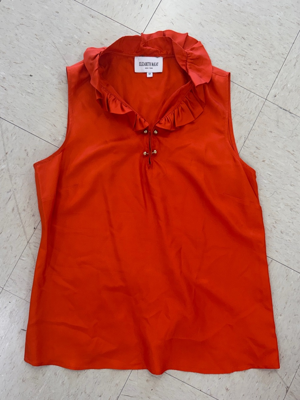 Elizabeth McKay red-orange ruffled silk blouse features a sleeveless design